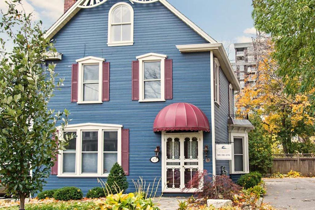 Downtown Burlington century home rental with gingerbread details and restored blue clapboard siding.